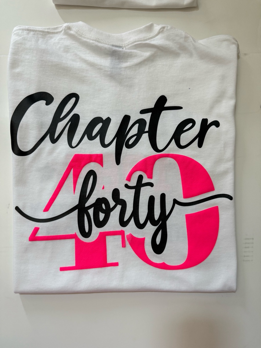 A white tee printed chapter forty in black script over a large hot pink 40.