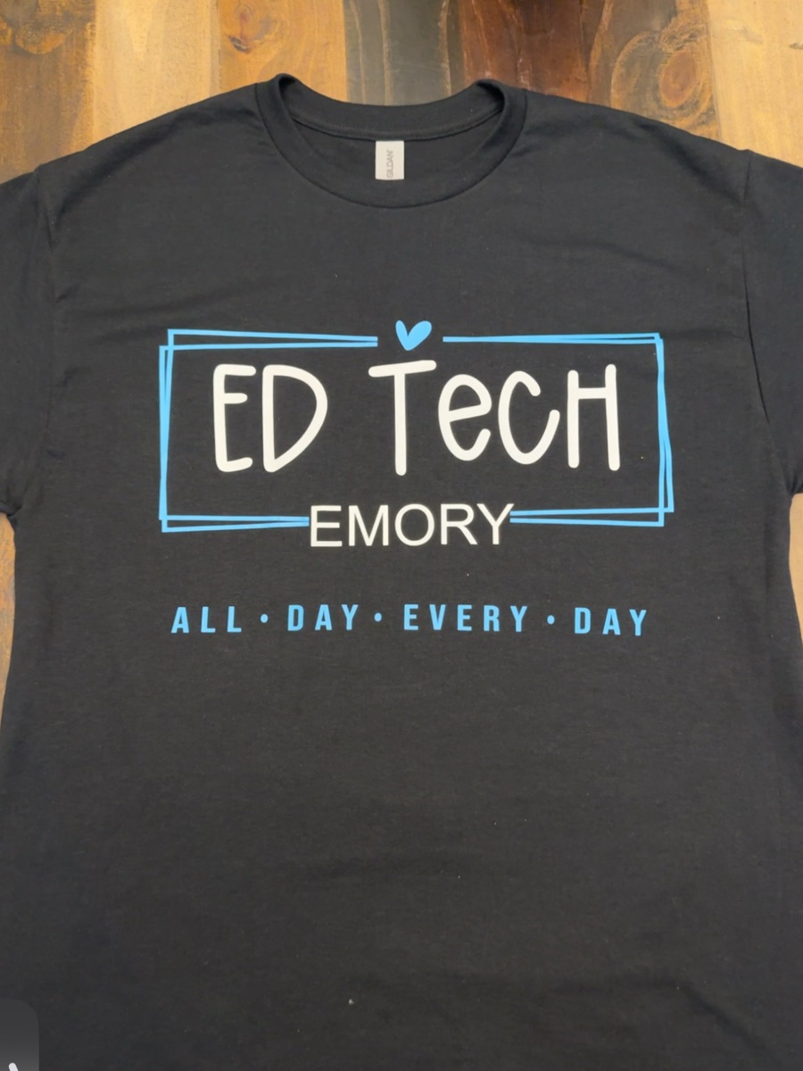 A black tee printed ED Tech, Emory, all day every day in white and light blue inside a sketched double frame.
