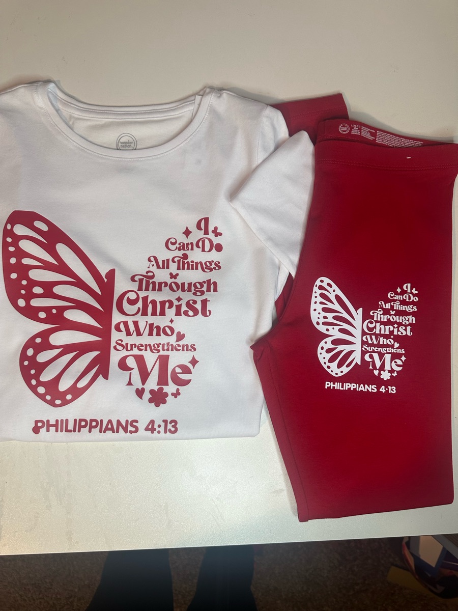 A white tee and red pants printed with a butterfly made of the words I can do all things through Christ who strengthens me, Philippians 4:13.