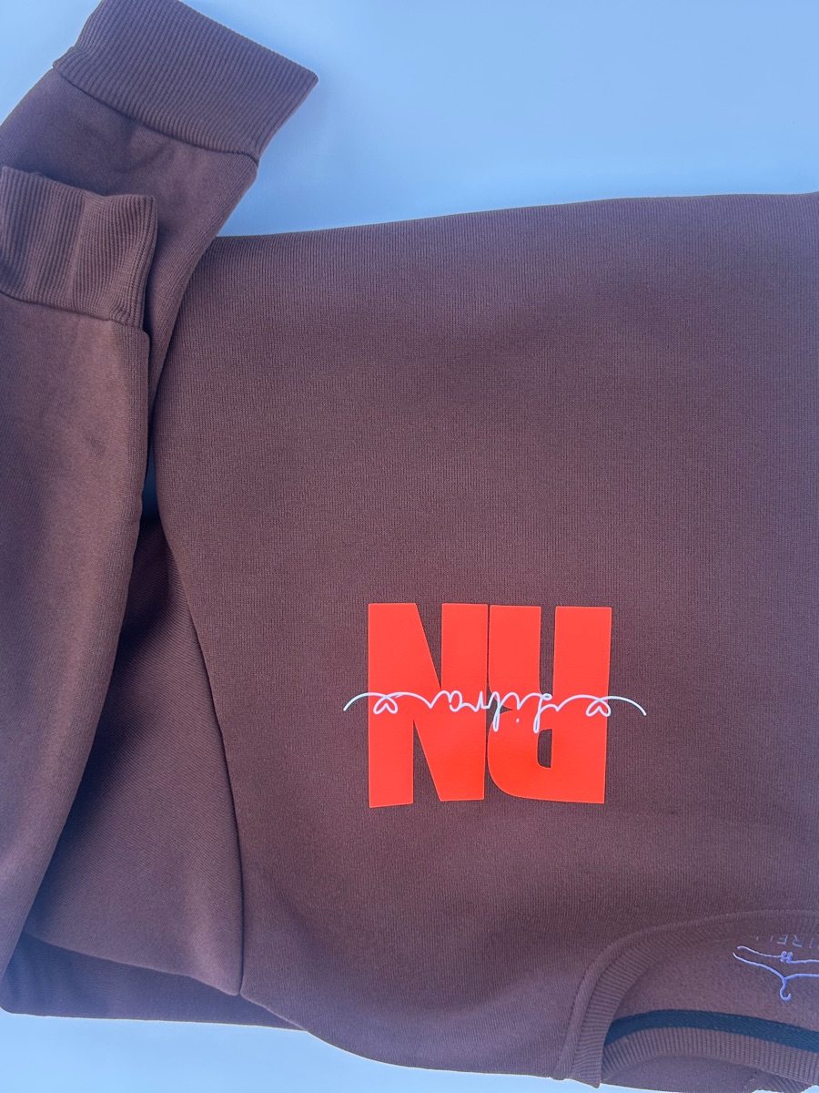 The front of the same brown hoodie, folded, with a small orange-red RN and a white heartbeat line on the chest.