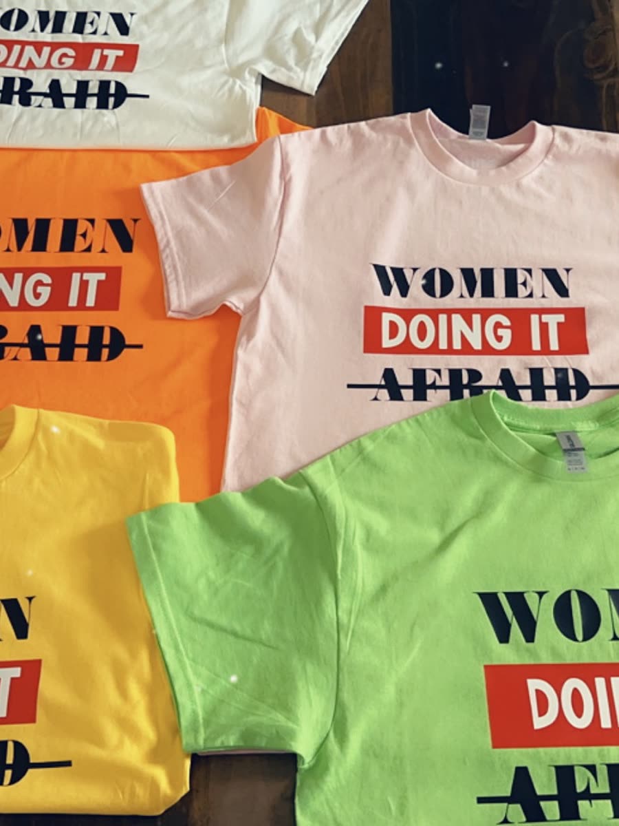 Six tees in white, orange, pink, yellow and green, each printed with women doing it afraid.
