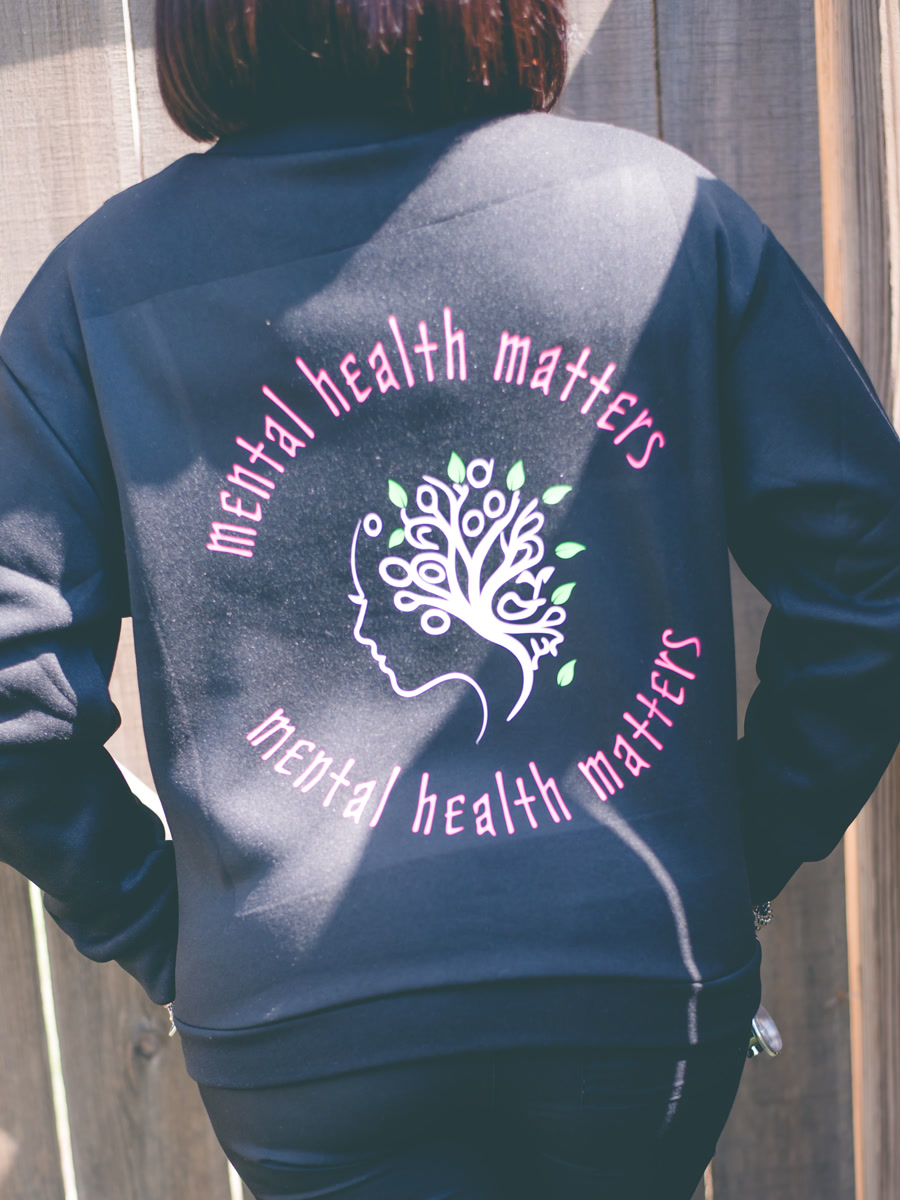 The back of a black pullover, printed with a tree-of-life face design ringed by the words mental health matters.
