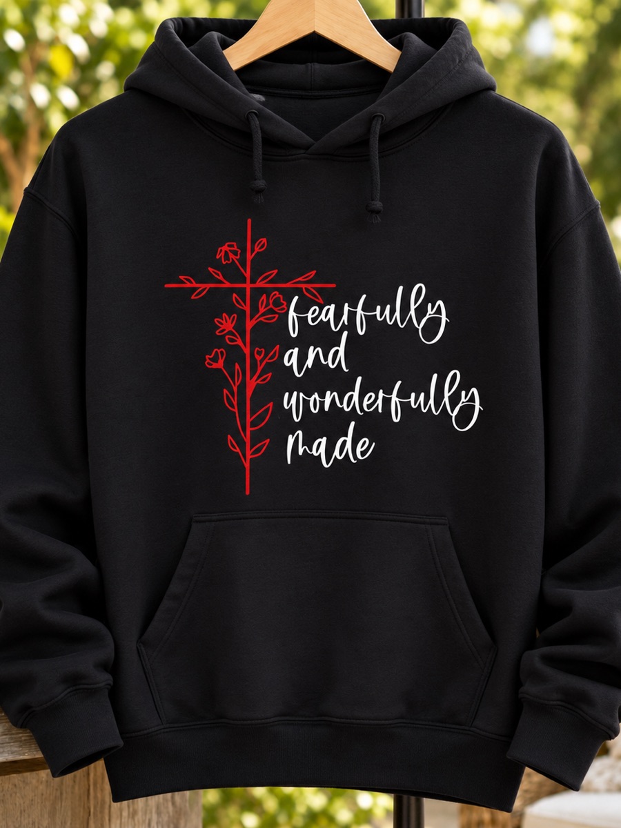 A black hoodie printed fearfully and wonderfully made in white script beside a red cross of flowering vines.