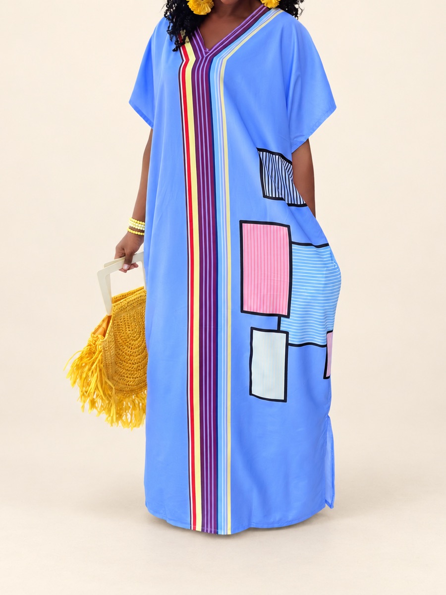 A woman in a blue maxi kaftan with a multicolored striped band and pastel patchwork panels down the front.